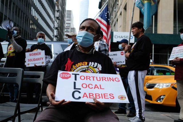 A man holding a sign that says "Torturing Local Cabbies"